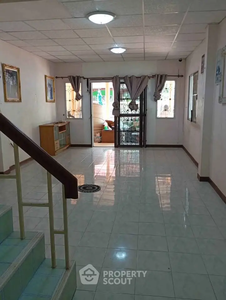 Spacious living room with tiled flooring and natural light, ideal for family gatherings.