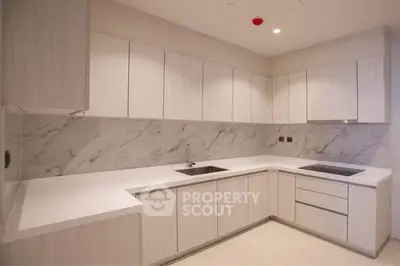 Modern kitchen with sleek white cabinetry and marble backsplash