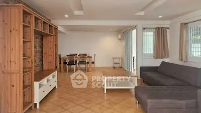 Spacious living room with wooden furniture and tiled flooring, perfect for family gatherings.