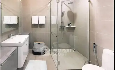 Modern bathroom with glass shower, sleek vanity, and neutral tiles.