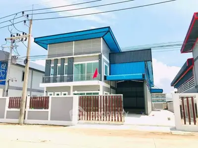 Modern industrial-style building with blue accents and spacious driveway.