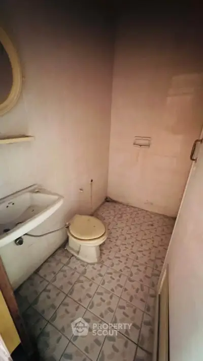 Compact bathroom with tiled floor and basic fixtures, ideal for small spaces.