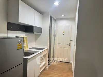 Compact modern kitchen with sleek cabinetry and stainless steel appliances in a cozy apartment.