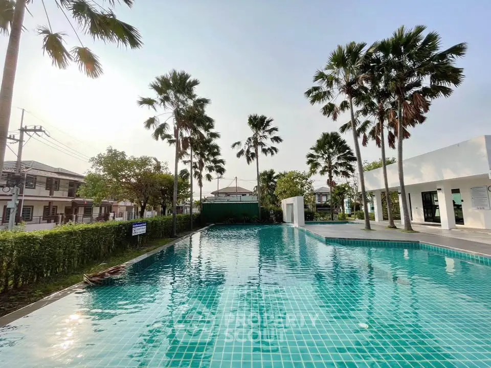 Luxurious residential pool surrounded by palm trees and modern architecture, perfect for relaxation and leisure.