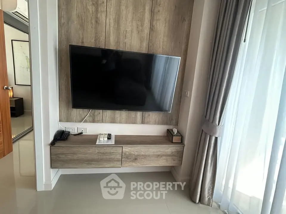 Modern living room with wall-mounted TV and elegant curtains in a stylish apartment.