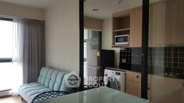 Modern apartment interior with open kitchen and cozy living area, featuring a washing machine and microwave.