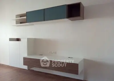 Modern minimalist living room with sleek wall-mounted cabinets and wooden flooring.