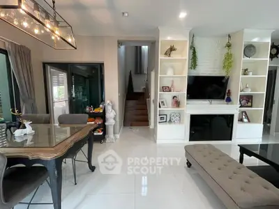 Elegant living room with modern decor, large dining table, and built-in shelves around a flat-screen TV.