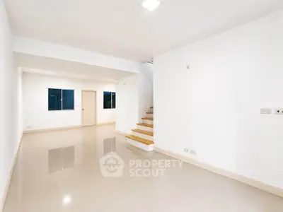 Spacious modern living room with glossy tiled floors and staircase in minimalist design.