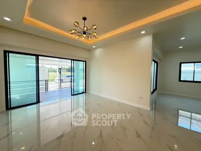 Spacious modern living room with elegant lighting and marble flooring, opening to a large balcony.