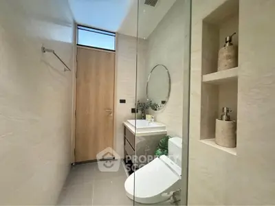 Modern bathroom with sleek design, featuring a round mirror and elegant fixtures.