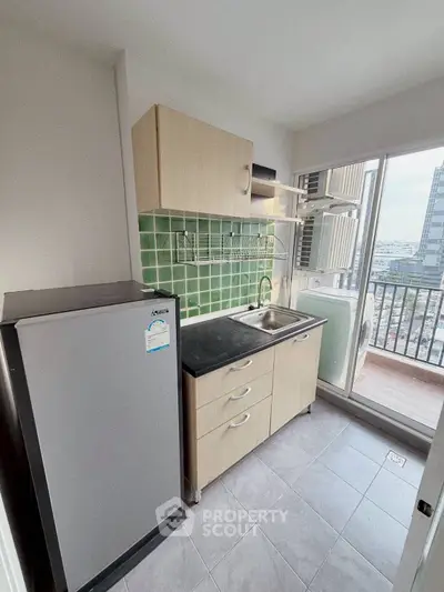 Compact kitchen with green tile backsplash and balcony view in modern apartment