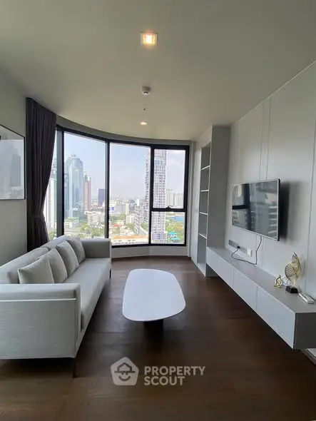 Modern living room with panoramic city view, sleek furniture, and large windows in a high-rise apartment.