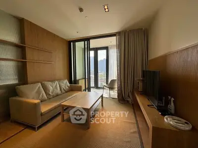 Modern living room with beige sofa, wooden accents, and balcony view in urban apartment.