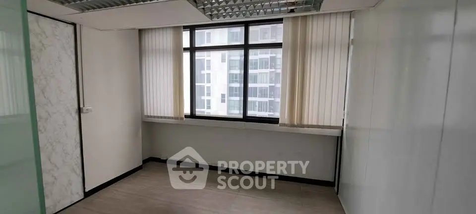 Spacious office room with large window and modern design in a high-rise building.