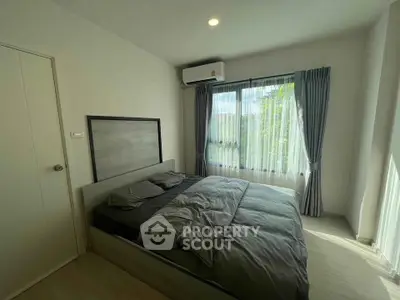 Cozy bedroom with natural light and modern decor, featuring a comfortable bed and air conditioning.
