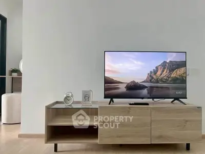 Modern living room with sleek TV stand and flat-screen TV displaying scenic view.
