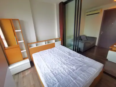 Modern bedroom with wooden furniture and sliding glass door to cozy living area.