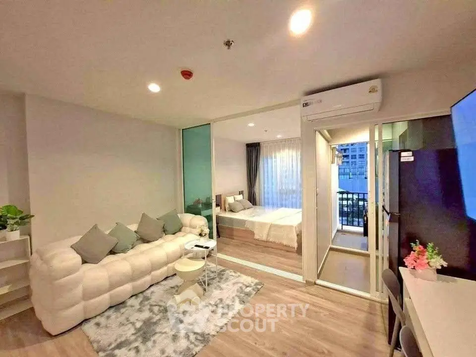 Modern open-plan living room with cozy bedroom and balcony view in stylish apartment.