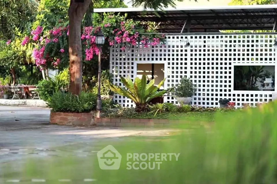 Charming garden view with lush greenery and modern lattice facade, perfect for tranquil living.