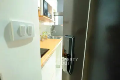 Modern kitchen with sleek appliances and digital door lock, showcasing contemporary design and functionality.