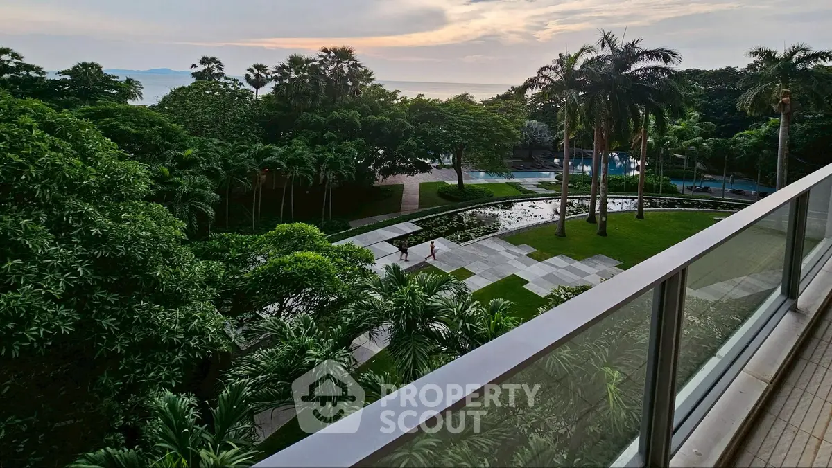 Luxurious balcony view overlooking lush gardens and serene ocean horizon at sunset.