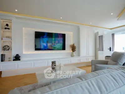 Luxurious living room with modern decor and large wall-mounted TV, featuring elegant built-in shelving and cozy seating.