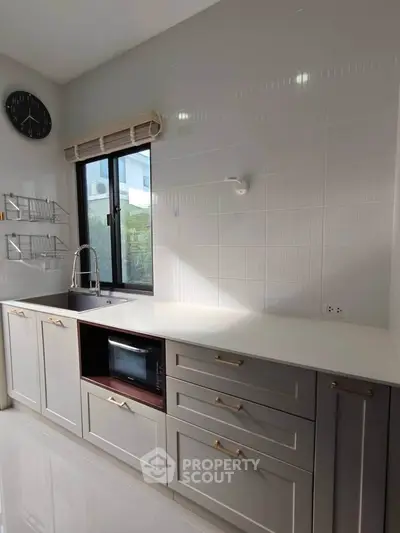 Modern kitchen with sleek cabinetry, large window, and built-in microwave, offering a bright and functional space.