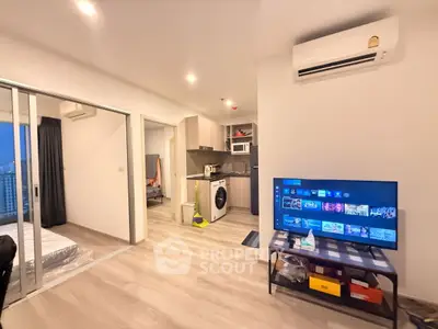 Modern apartment interior with open layout, featuring a kitchen, living area, and bedroom view.