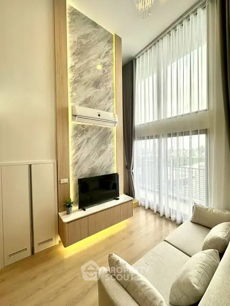 Luxurious living room with high ceilings and modern decor, featuring large windows and elegant lighting.