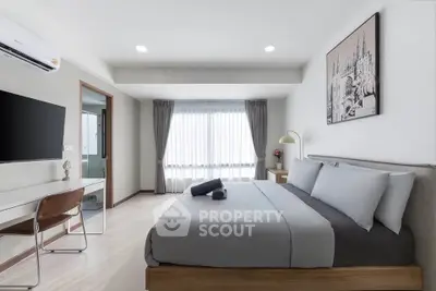 Modern bedroom with stylish decor and natural light, featuring a comfortable bed and workspace.