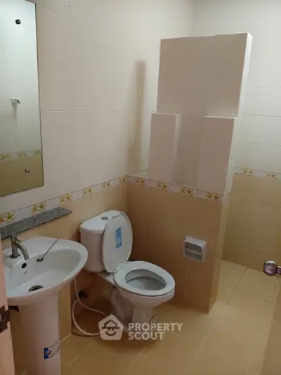 Modern bathroom with pedestal sink and toilet in a tiled interior.