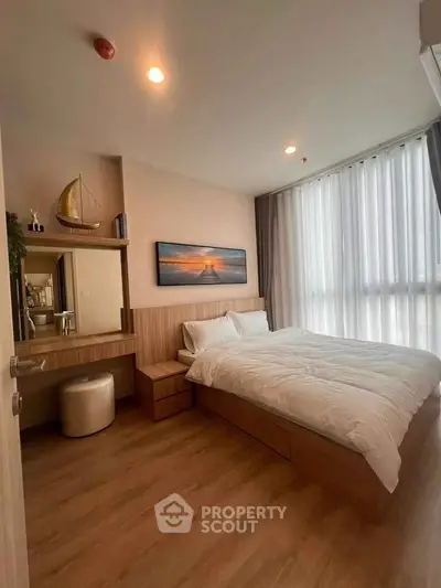 Modern bedroom with wooden flooring, large window, and stylish decor in a cozy apartment.