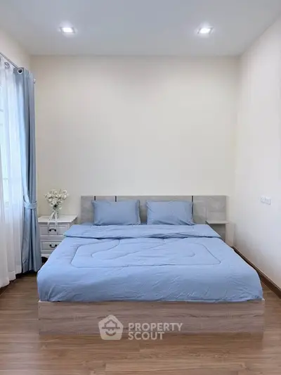 Cozy bedroom with modern decor and soft blue bedding, perfect for relaxation.