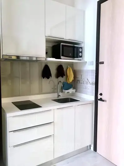 Modern compact kitchen with sleek white cabinets and built-in appliances, perfect for urban living.
