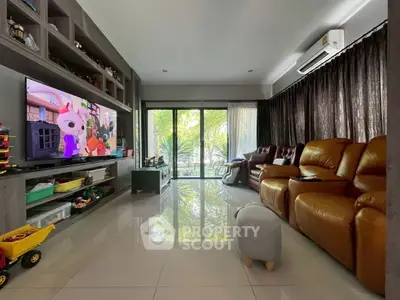 Spacious living room with modern decor and large windows overlooking greenery.