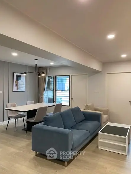 Modern living room with stylish furniture and dining area, featuring a cozy blue sofa and elegant decor.