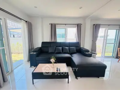 Spacious modern living room with black leather sectional sofa and large windows