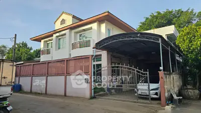 Charming two-story house with gated driveway and lush greenery