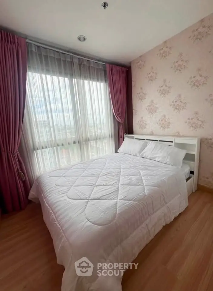 Cozy bedroom with floral wallpaper and large window, featuring elegant pink curtains and a comfortable bed.