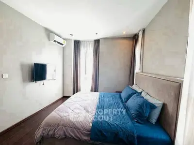 Modern bedroom with stylish decor and wall-mounted TV, featuring a cozy bed and natural light.