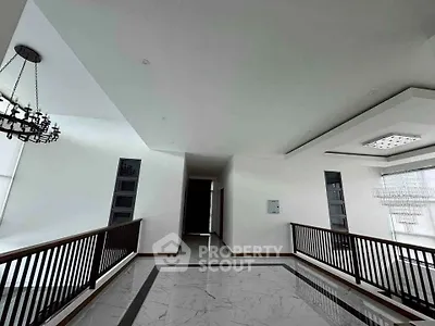 Spacious modern hallway with elegant chandeliers and sleek marble flooring.