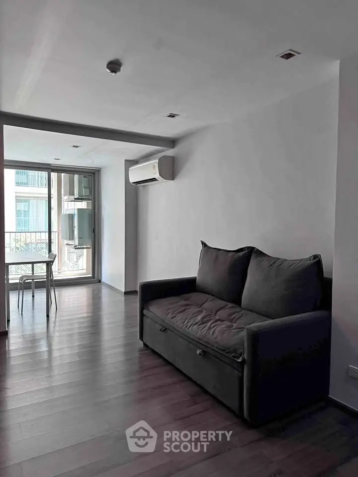 Modern living room with sleek sofa and large windows in a minimalist apartment.