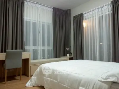Spacious bedroom with large windows and elegant curtains, featuring a cozy bed and a stylish desk.