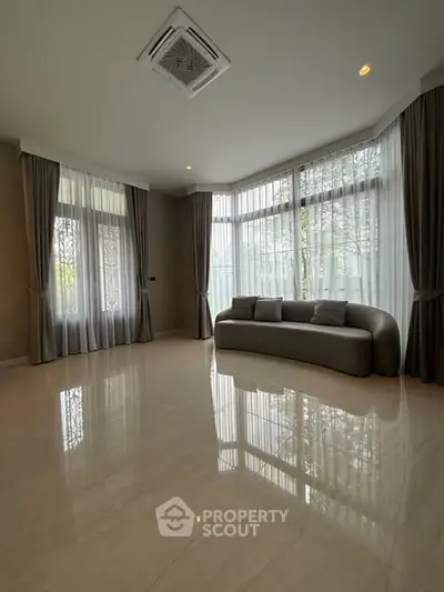 Spacious living room with elegant curtains and modern sofa, featuring large windows for natural light.