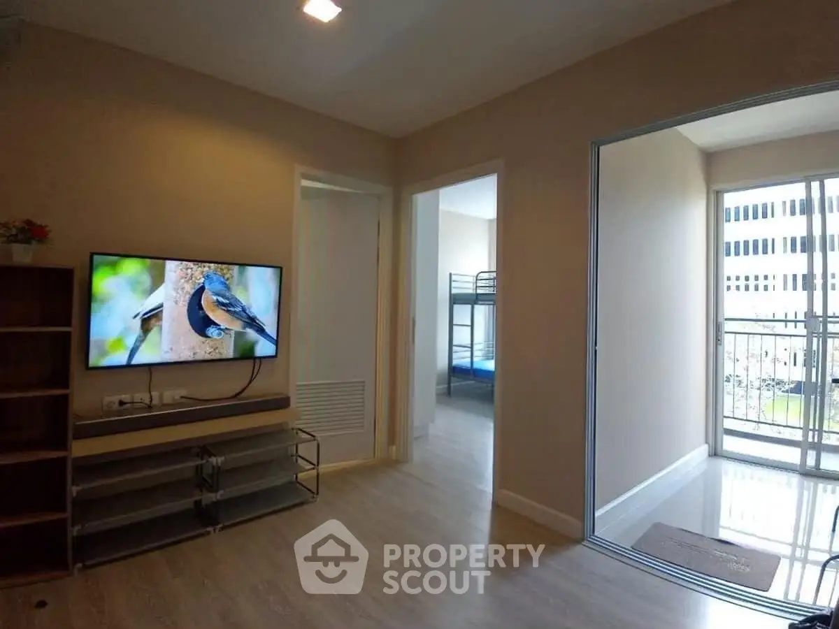 Modern living room with TV and balcony access in a bright apartment