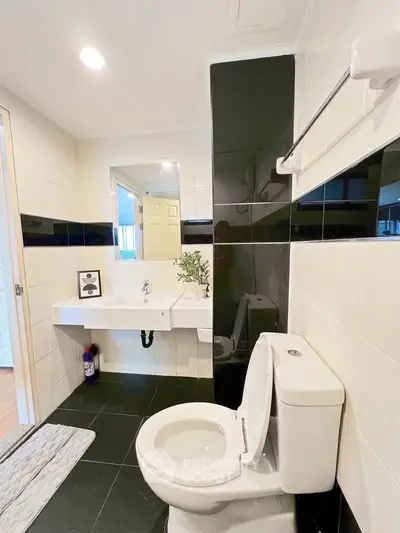 Modern bathroom with sleek black and white tiles, featuring a stylish sink and toilet.
