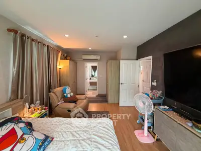 Cozy bedroom with modern decor, featuring a large TV and comfortable seating area.