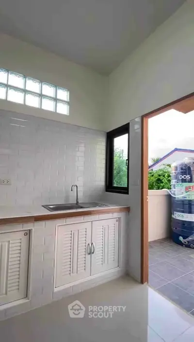 Bright kitchen with white cabinetry and outdoor access, perfect for modern living.