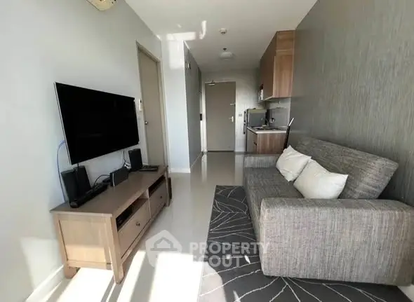 Modern living room with sleek furniture and wall-mounted TV in a cozy apartment.